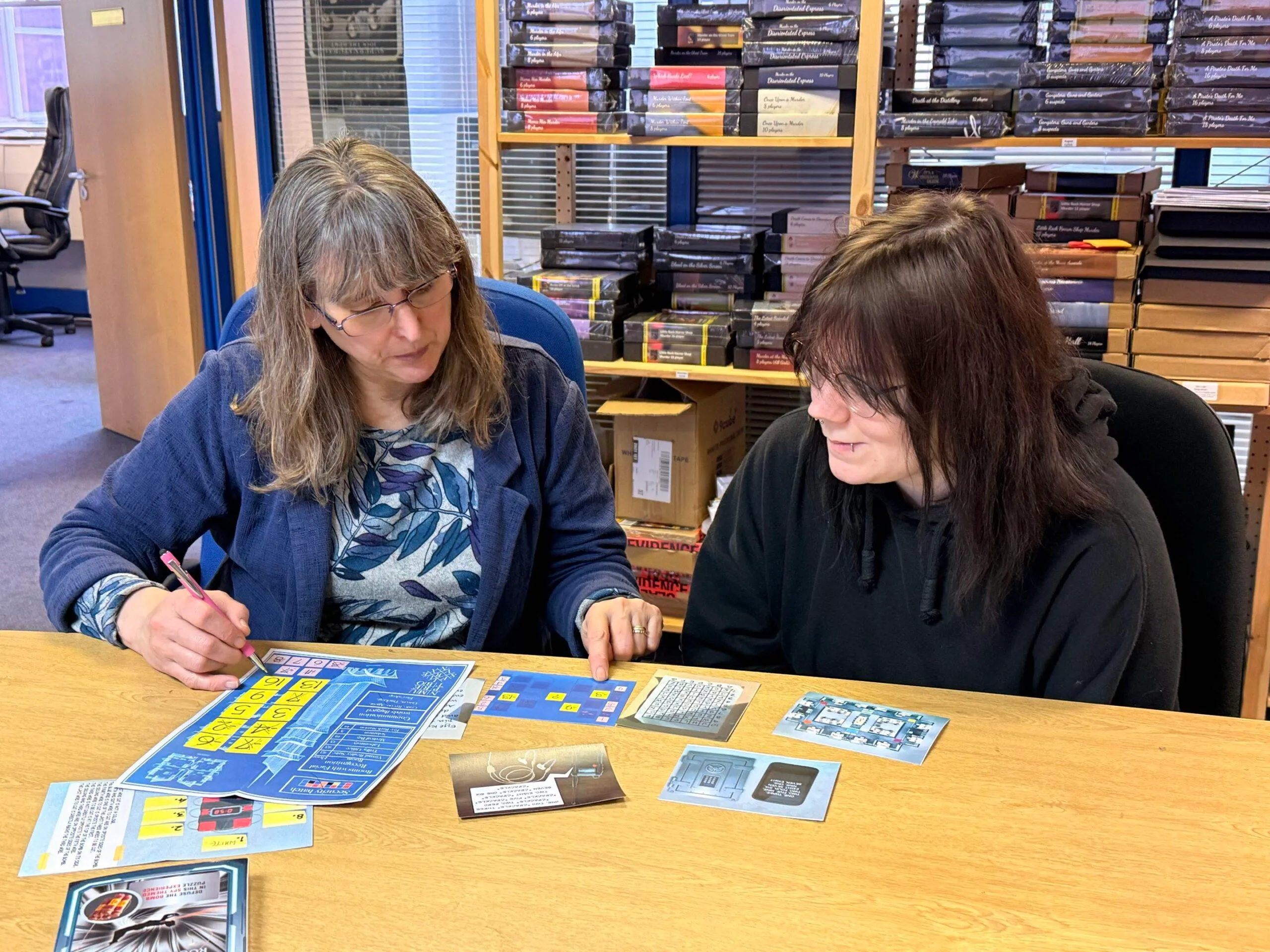 Two players working through the Mission Rogue Protocol puzzle cards together at a table